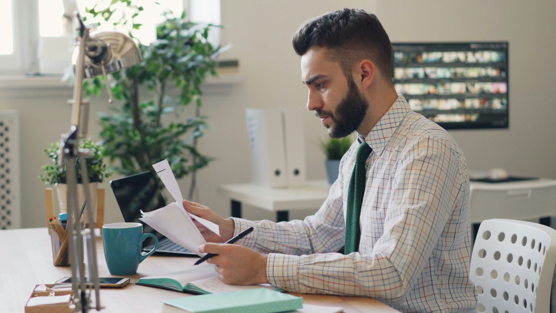 a man sitting at a desk with a laptop and papers