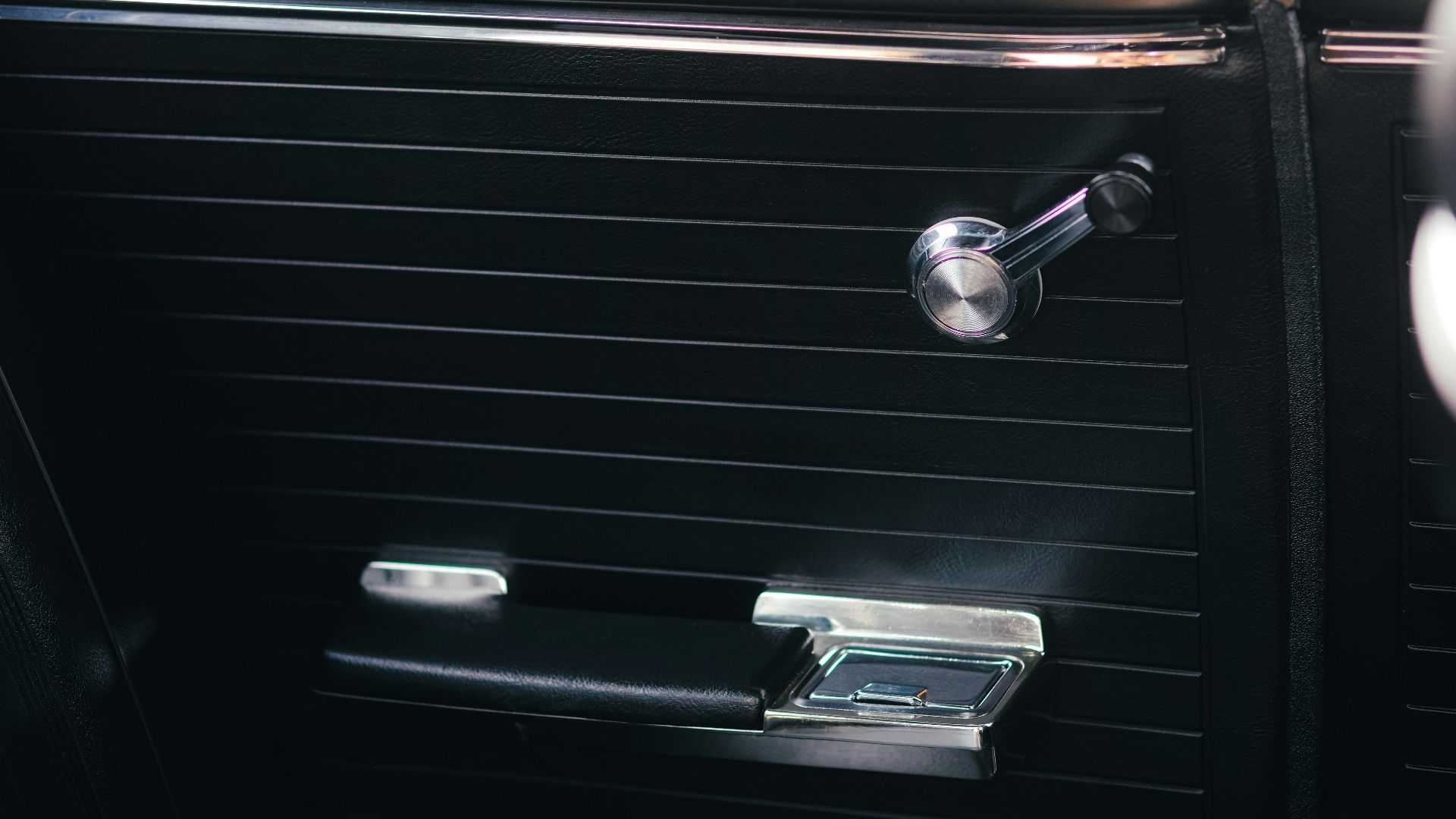 Close-up of vintage car door interior with chrome handle.