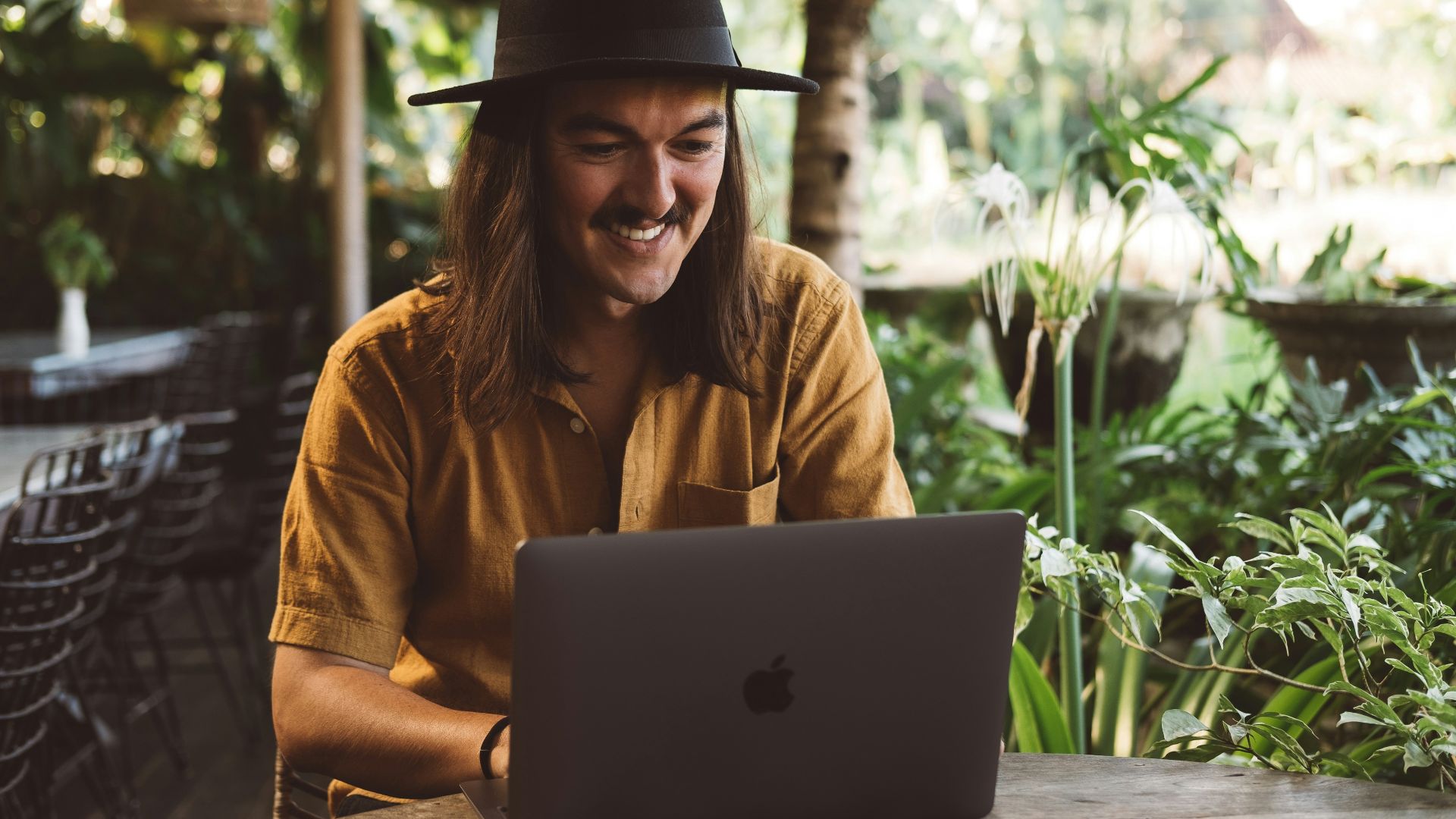 a man wearing a hat is looking at a laptop