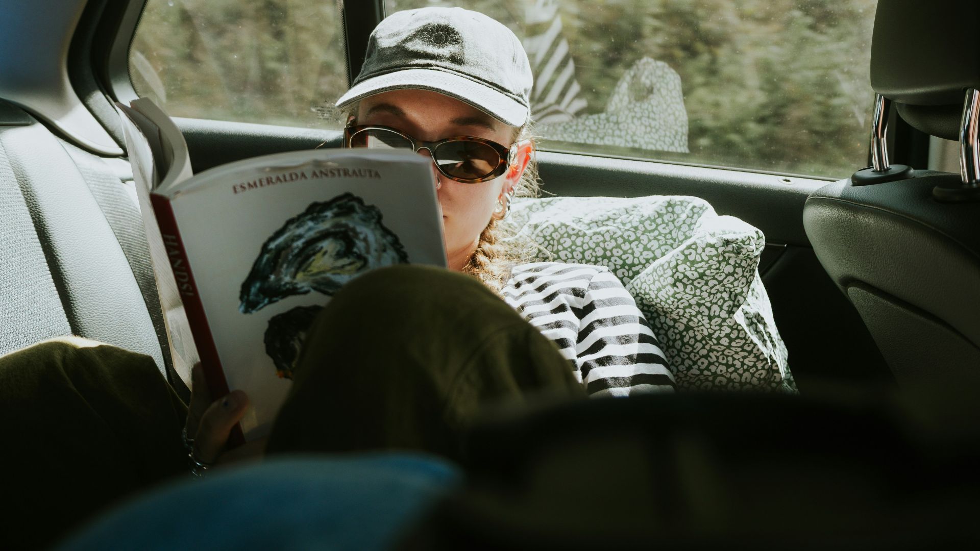 Person in car reading a book during a trip.
