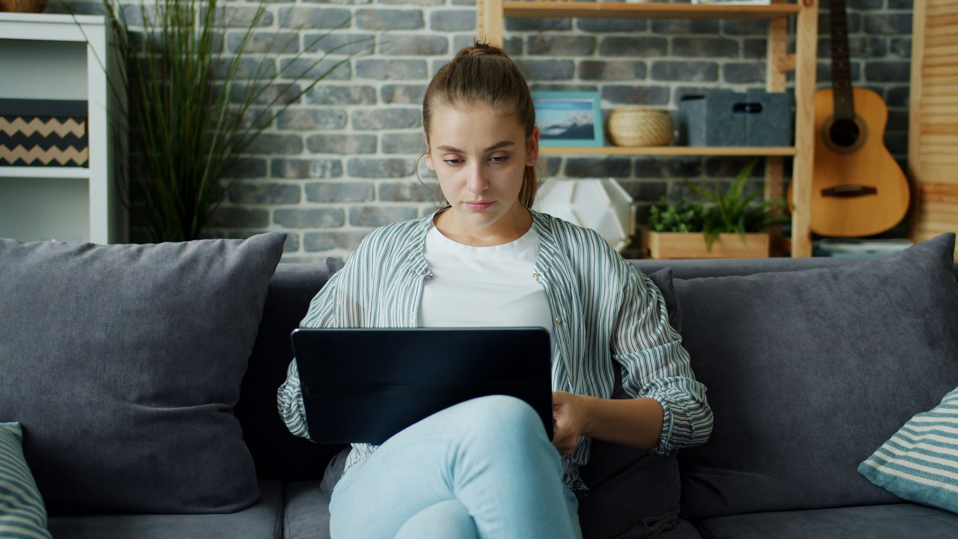 Young woman working on laptop on couch