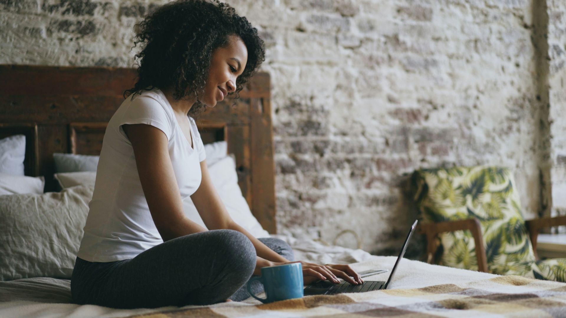 A woman working on a laptop in bed.