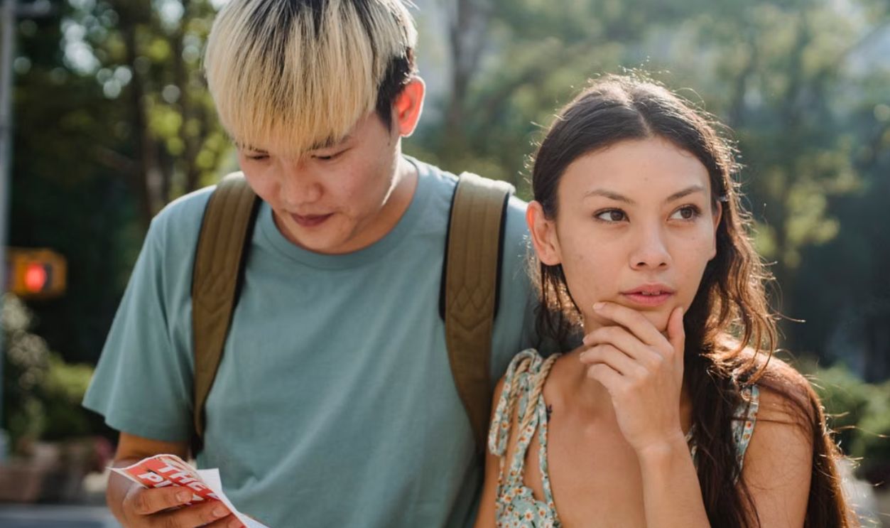 Young couple exploring city streets with a map, appearing thoughtful and focused