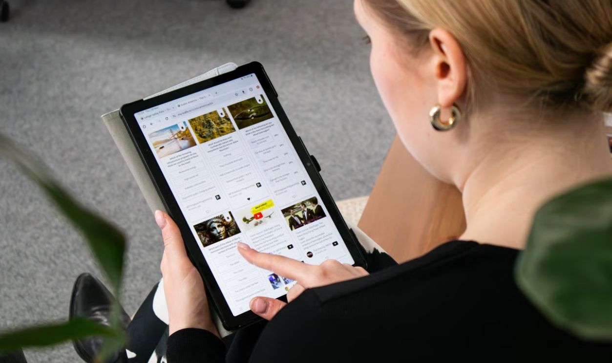 A woman browsing the web on a tablet, sitting in an office environment