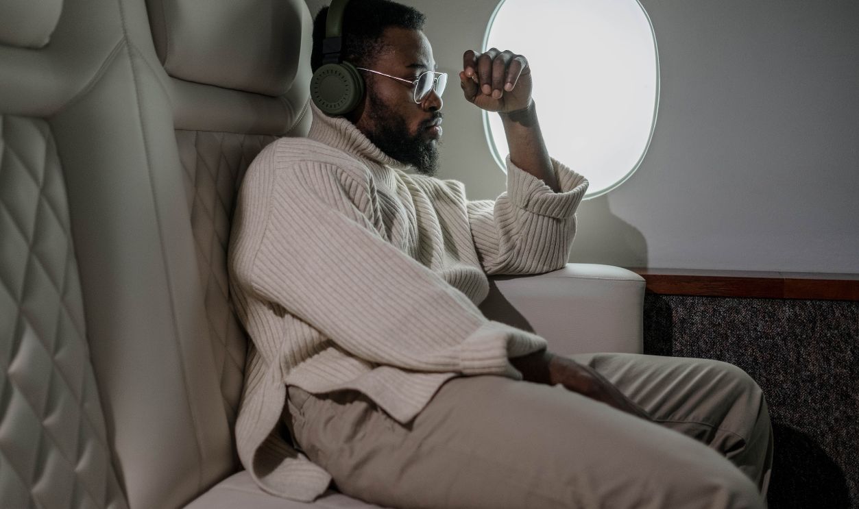 A man relaxing with headphones while traveling on a plane, enjoying leisure in comfort