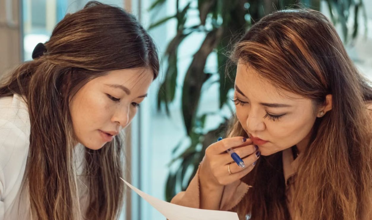 Two women collaborating in an office setting, focusing on documents.
