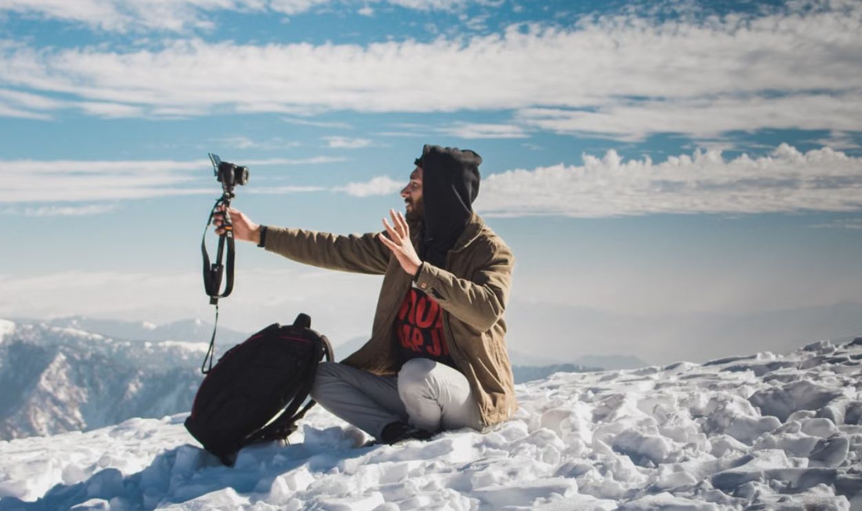 A vlogger captures content amidst the snowy peaks of Azad Jammu and Kashmir