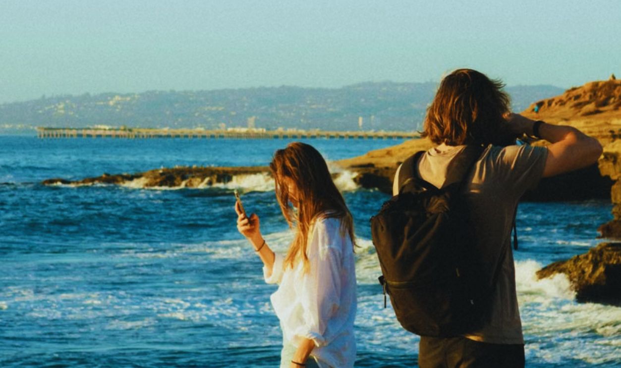 A man and woman capturing memories on a rocky seashore with stunning ocean views