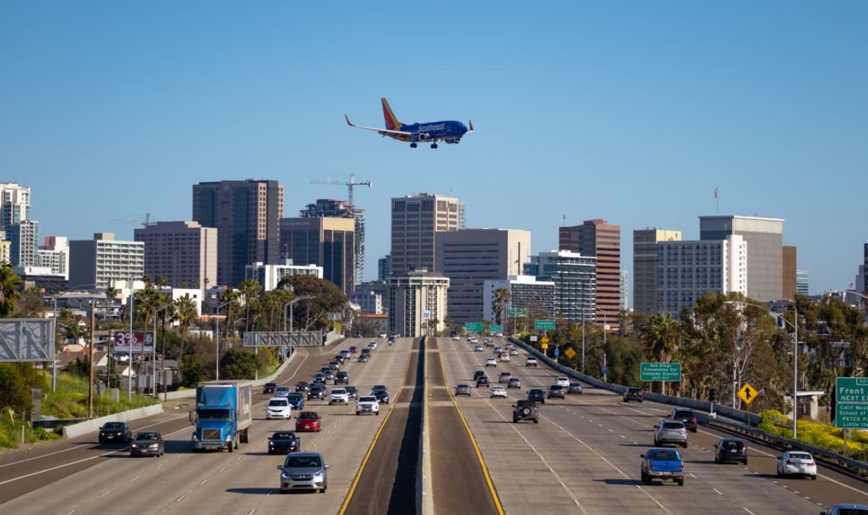 Airplane approaching San Diego airport over busy city freeway and skyline
