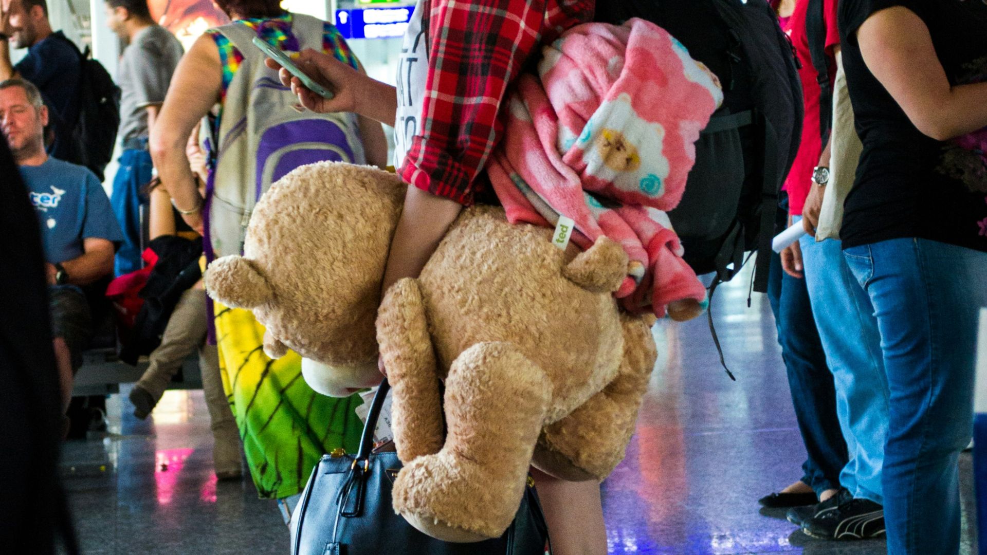 woman in black shirt holding brown bear plush toy