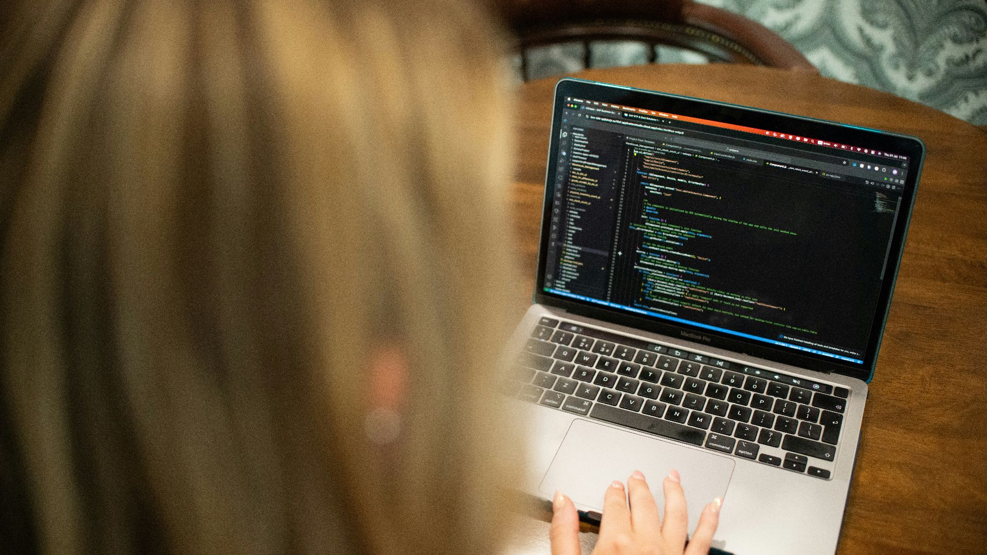 Woman typing code on a laptop computer.