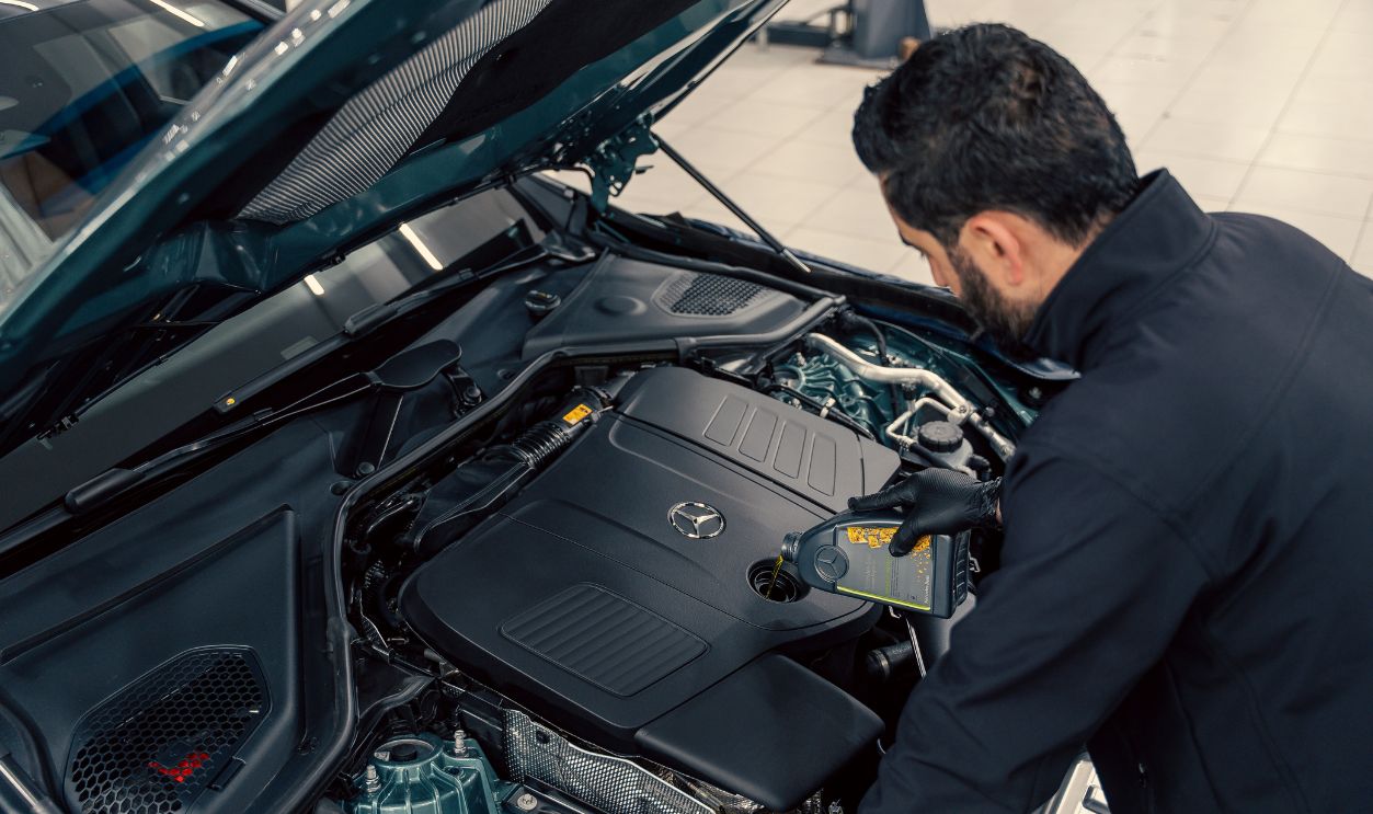 Mechanic inspecting and filling engine oil in a car at an indoor service center