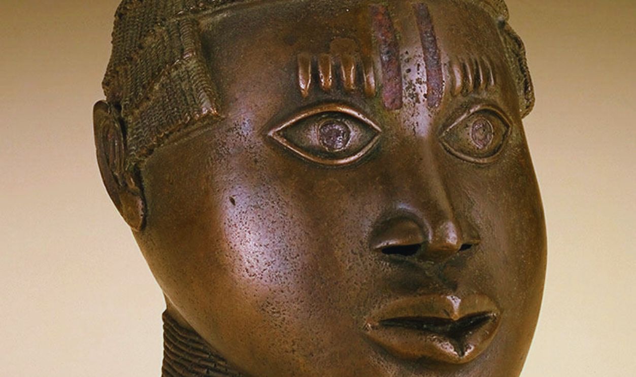 Gettyimages - 1338659822, Commemorative Trophy Head Naturalistic human head with circular opening in the top of the tiered twisted-strand hairstyle. A beaded collar covers the neck and two vertical iron inlay lines adorn the forehead over the nose with four raised keloids over each eye. Artist Unknown.