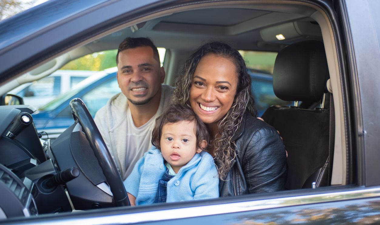 A joyful family with a baby in a car, expressing happiness and togetherness