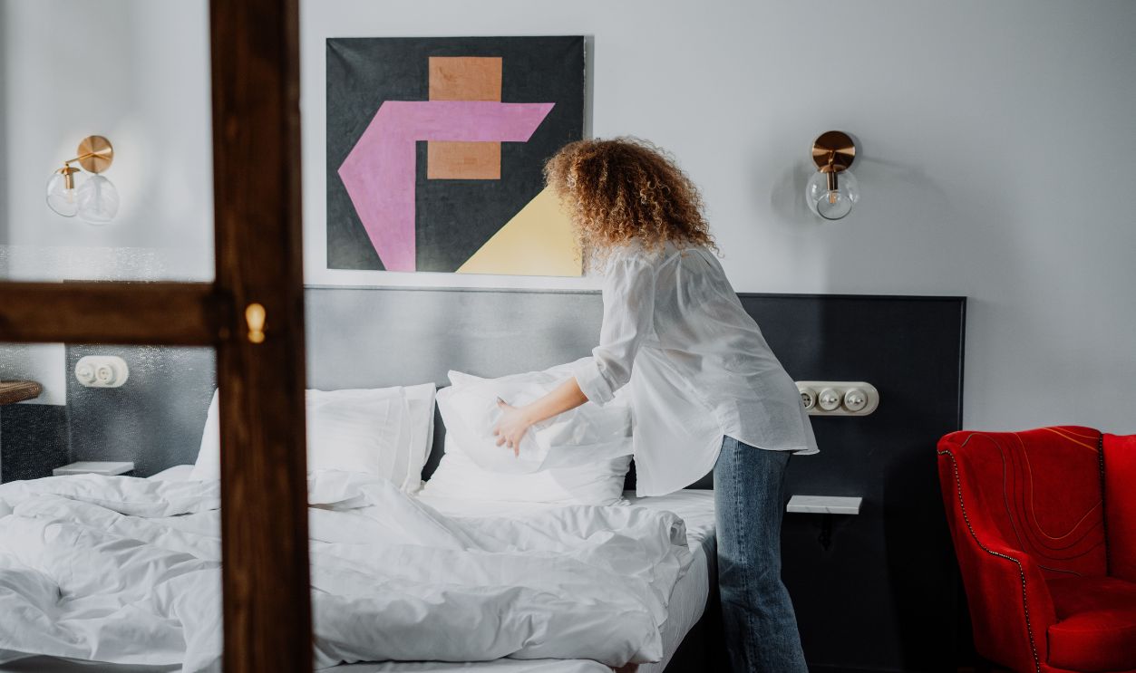 Woman adjusting pillows in a stylish bedroom with modern decor