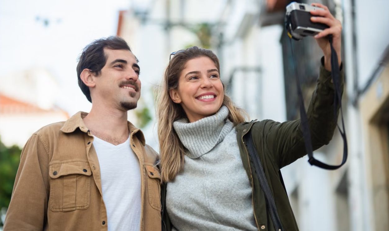 Smiling couple taking a photo together outside, enjoying a lovely autumn day