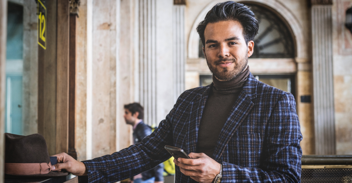 Attractive confident hispanic businessman wearing casual clothes buying train ticket on train station. Blurred background