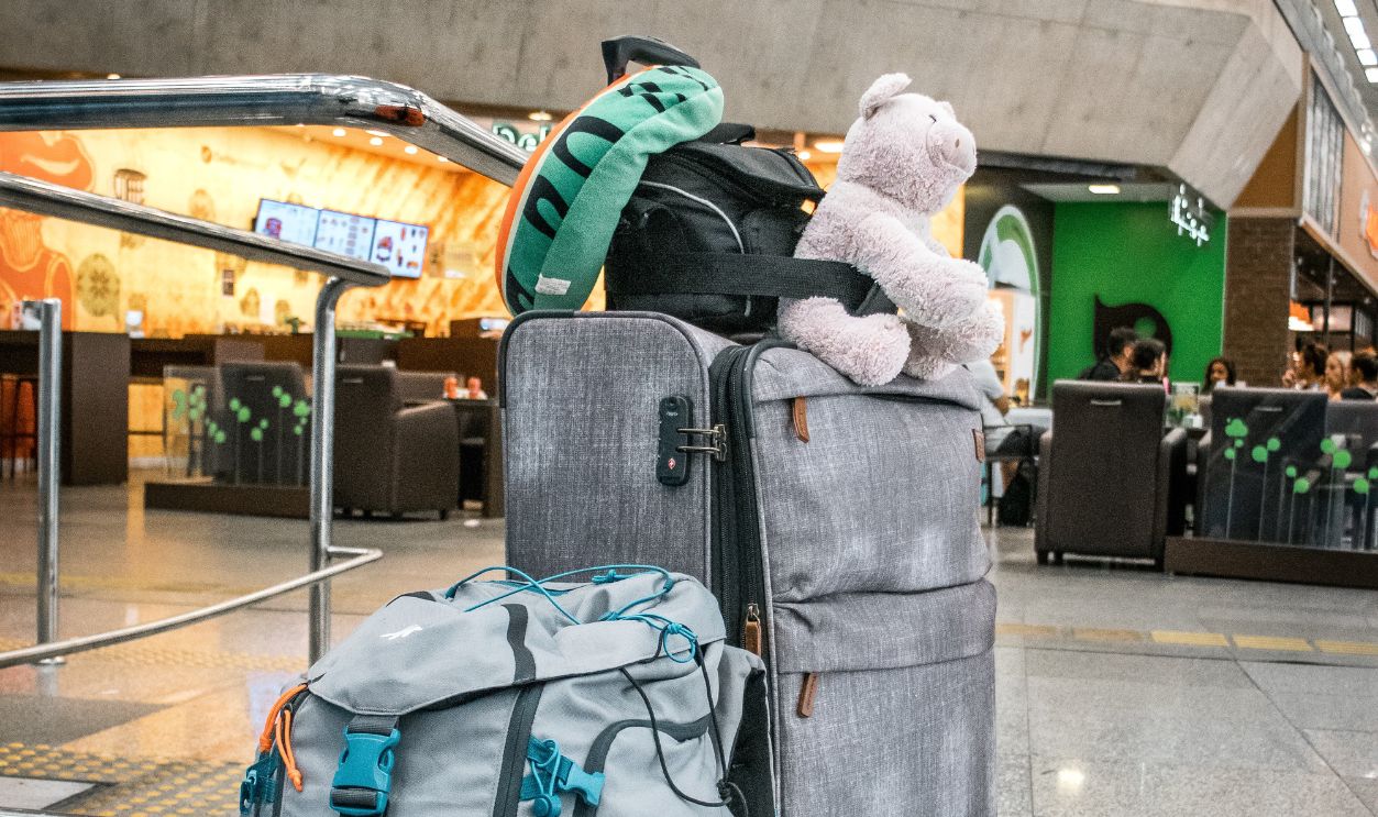 Travel bags with a teddy bear are ready for departure at a modern airport terminal.