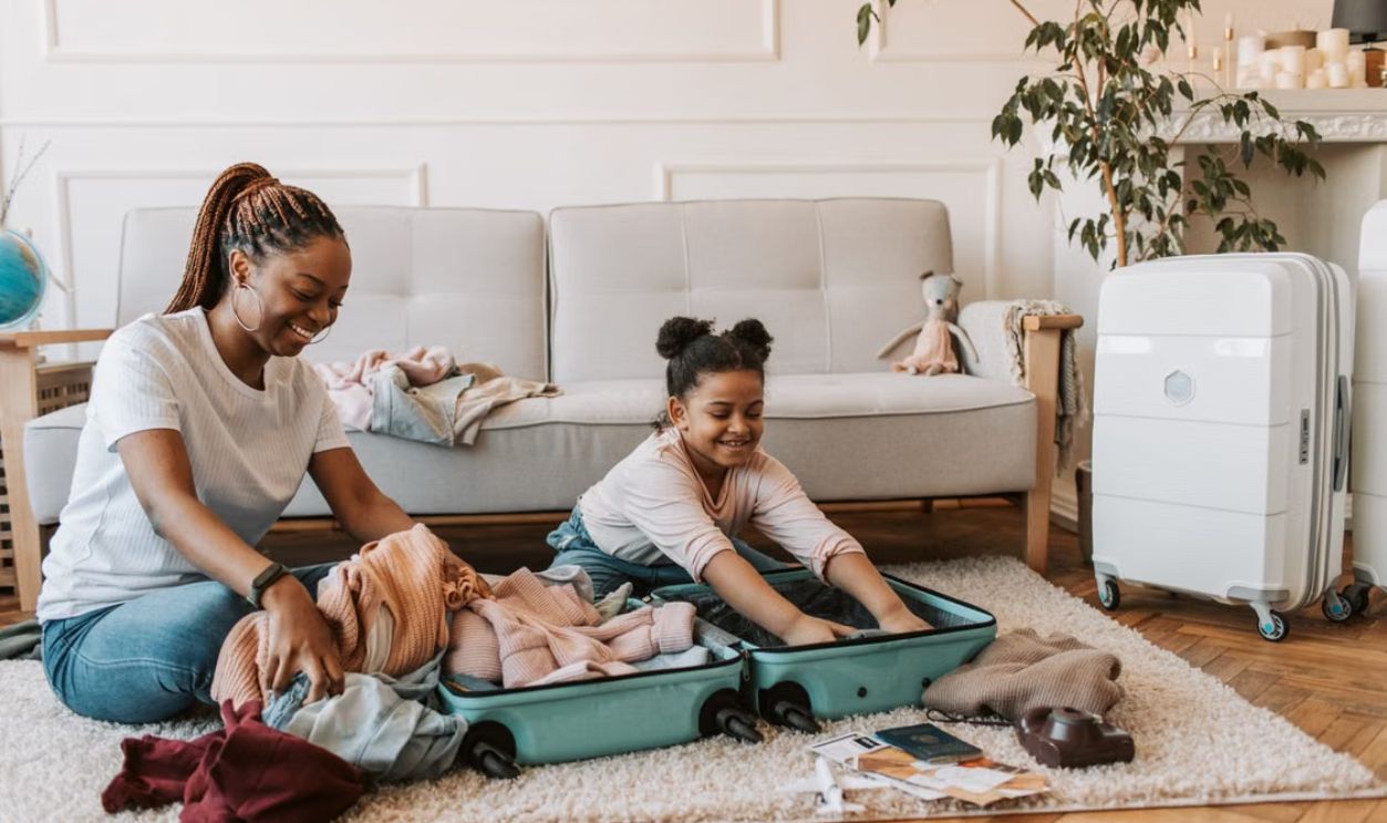A joyful moment of a mother and daughter packing luggage together in their living room.