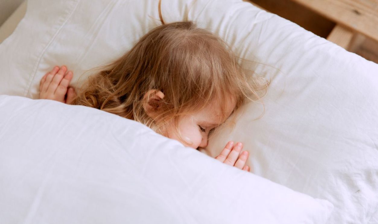 A young child peacefully sleeping under white blankets, embodying innocence and serenity