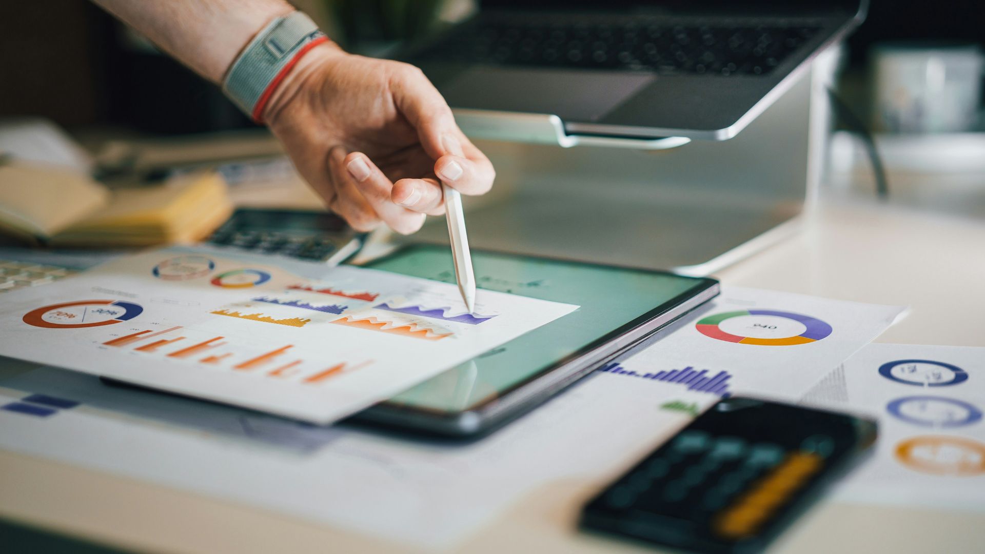 person using stylus on tablet with charts