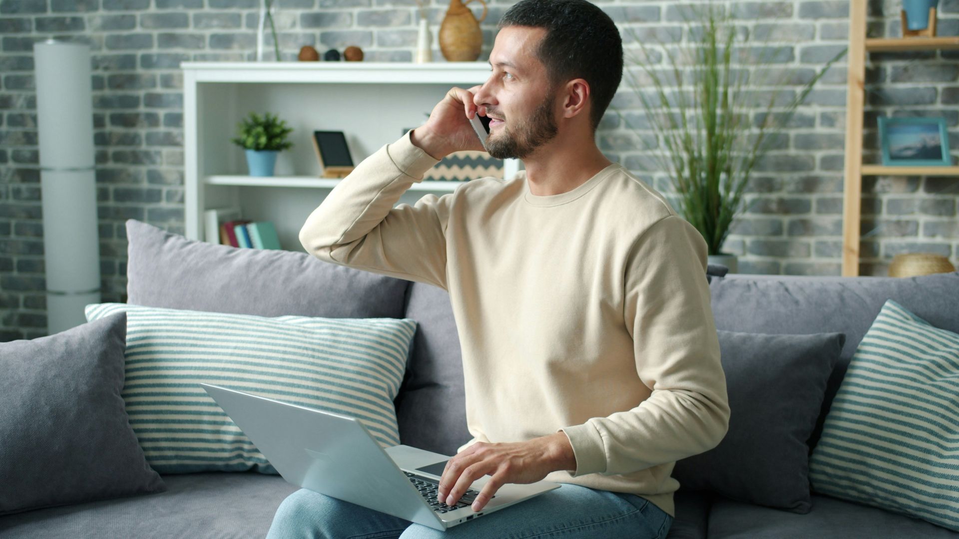 Man talking on phone with laptop on lap