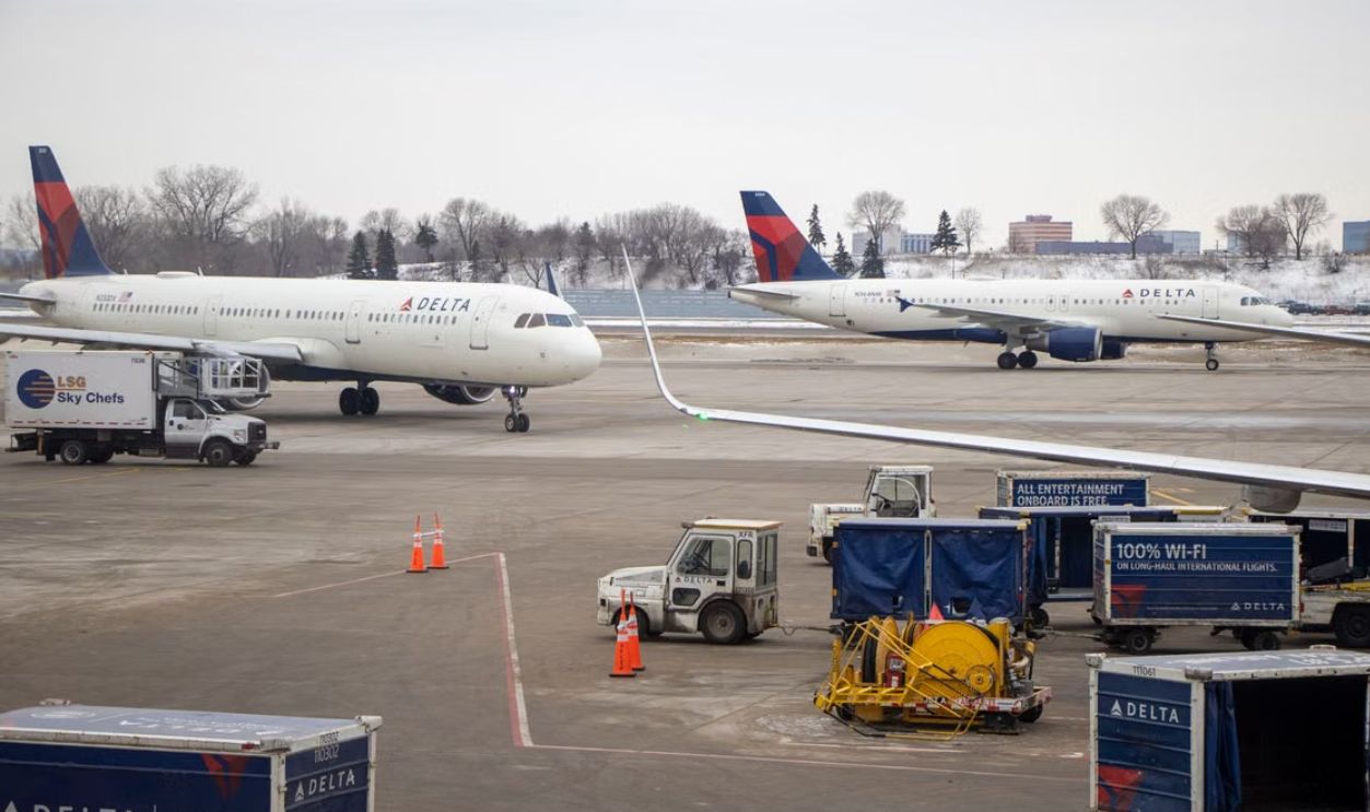 Delta airplanes on the snowy tarmac surrounded by service vehicles at a busy airport