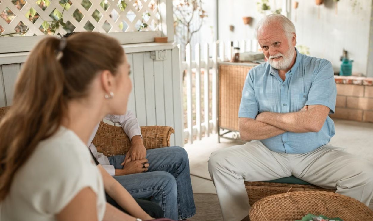 Senior man and two adults having a friendly conversation on a spacious veranda