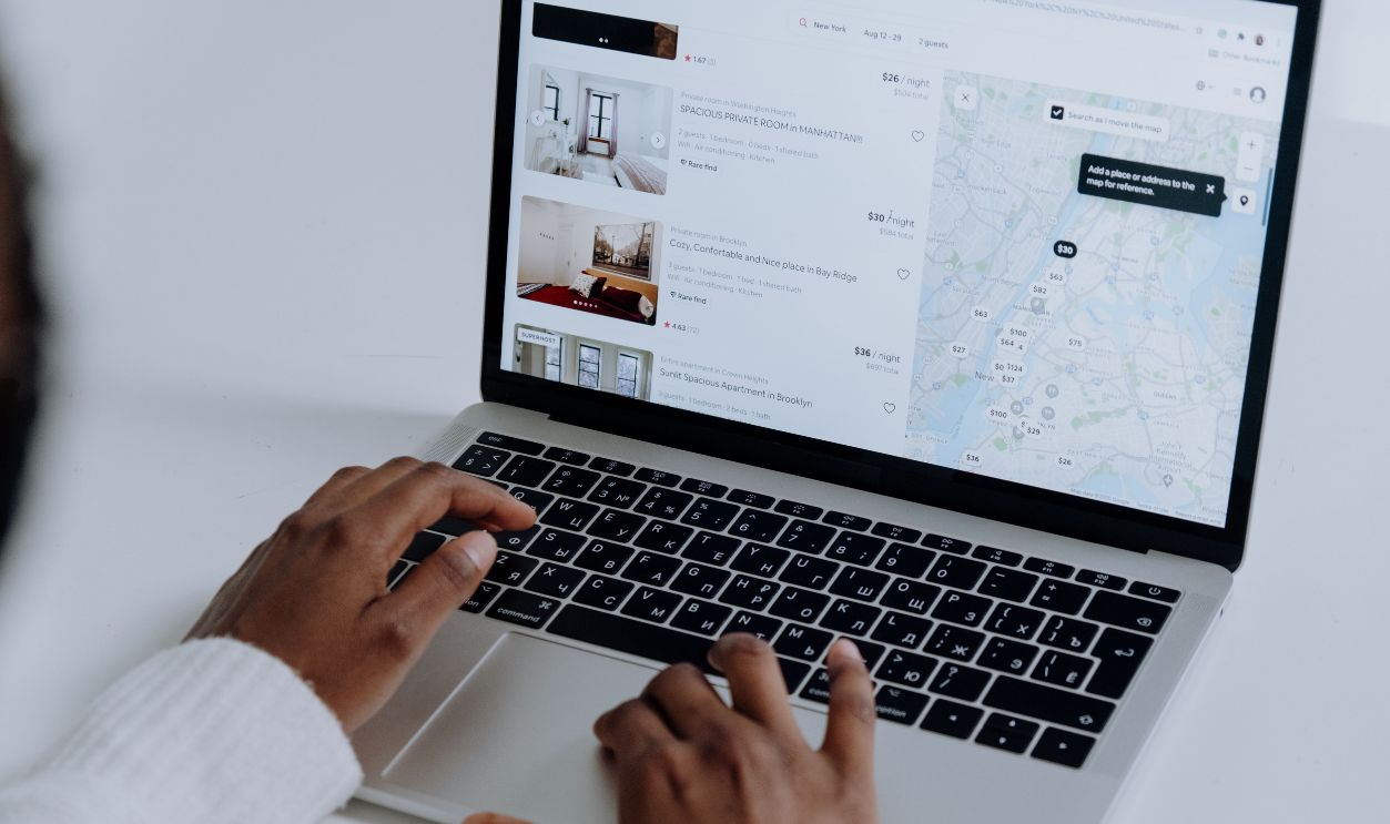 ands typing on laptop searching Airbnb for accommodation