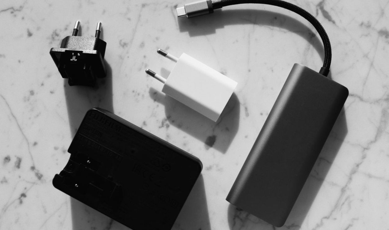 Flat lay of various electronic chargers on a marble surface 