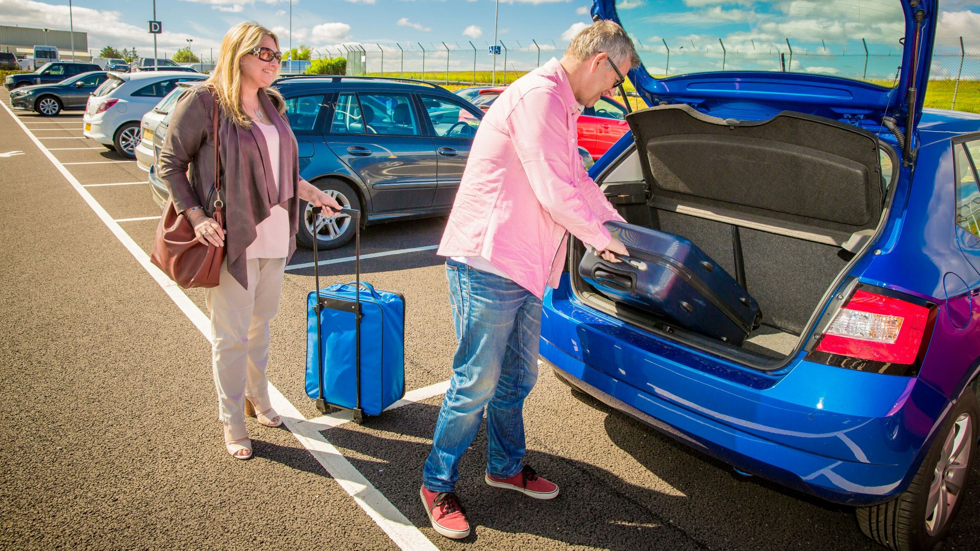 Couple loading luggage into a blue car