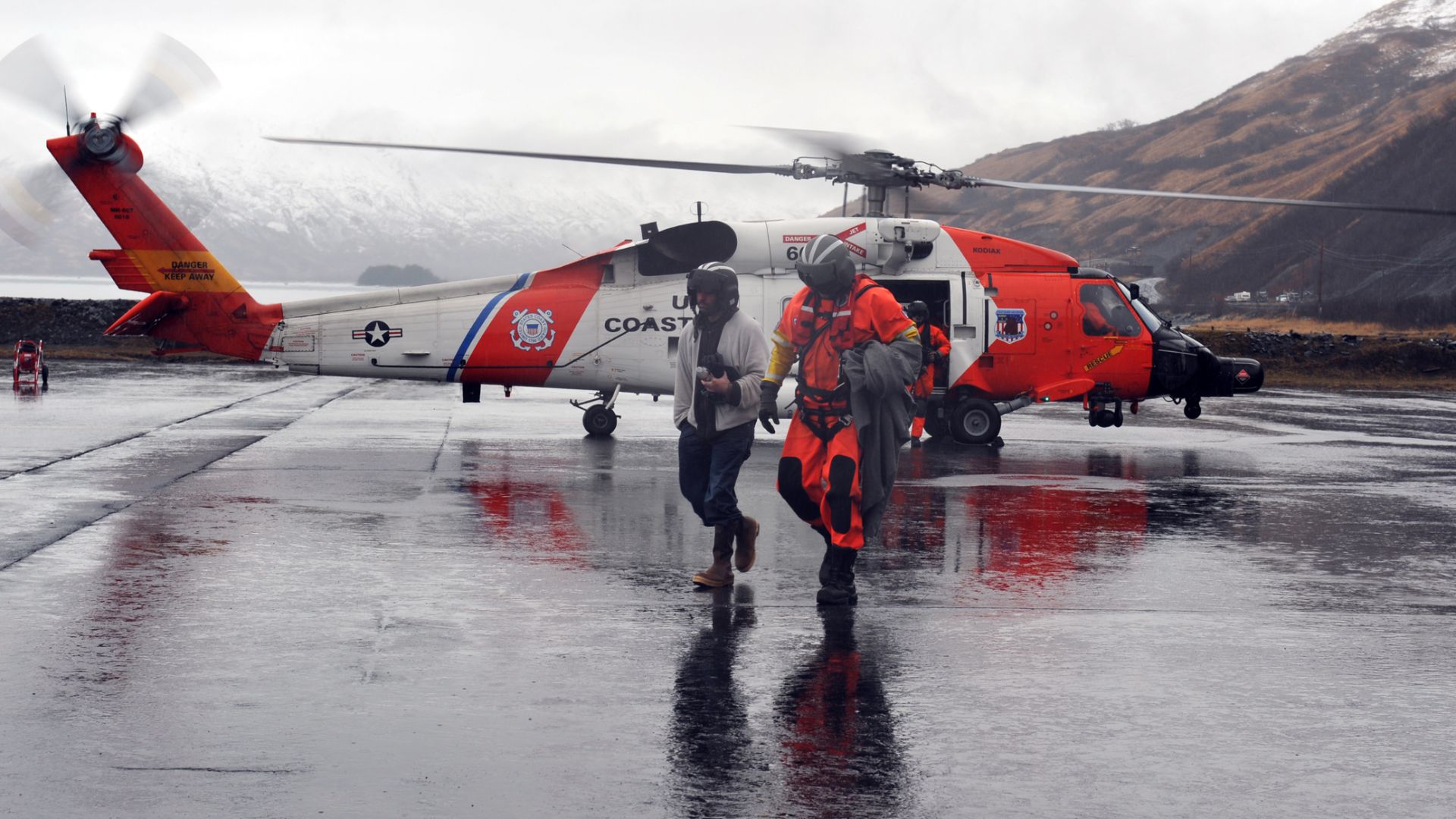 Petty Officer 1st Class Claude Morrissey, an aviation survival technician stationed at Coast Guard Air Station Kodiak, Alaska, escorts a rescued hiker from an MH-60 Jayhawk helicopter to awaiting emergency medical personnel on the air station runway, Apri