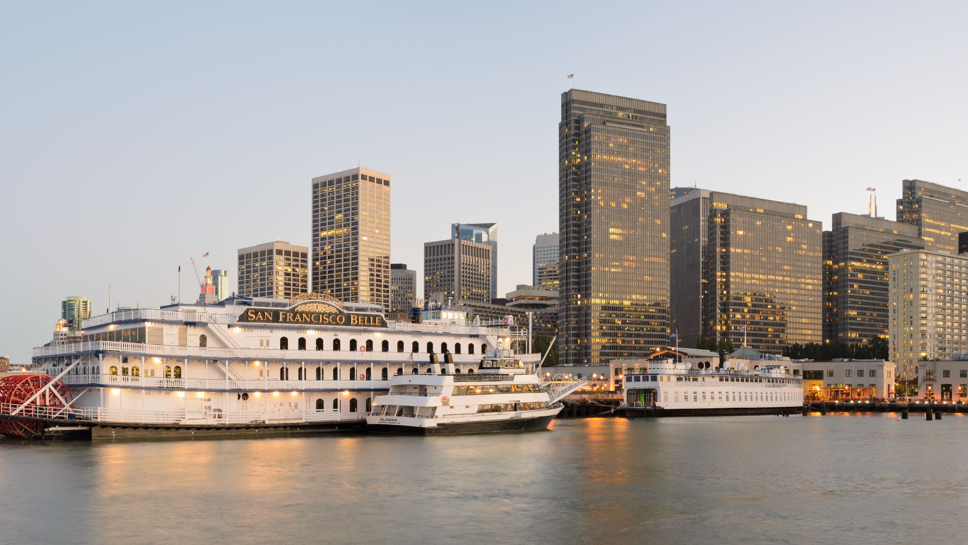 Two-segment panorama of San Francisco from Pier 7 at dusk. In the foreground one can see ships docked at Pier 3, with Financial District skyscrapers in the background. At the left is the Bay Bridge.