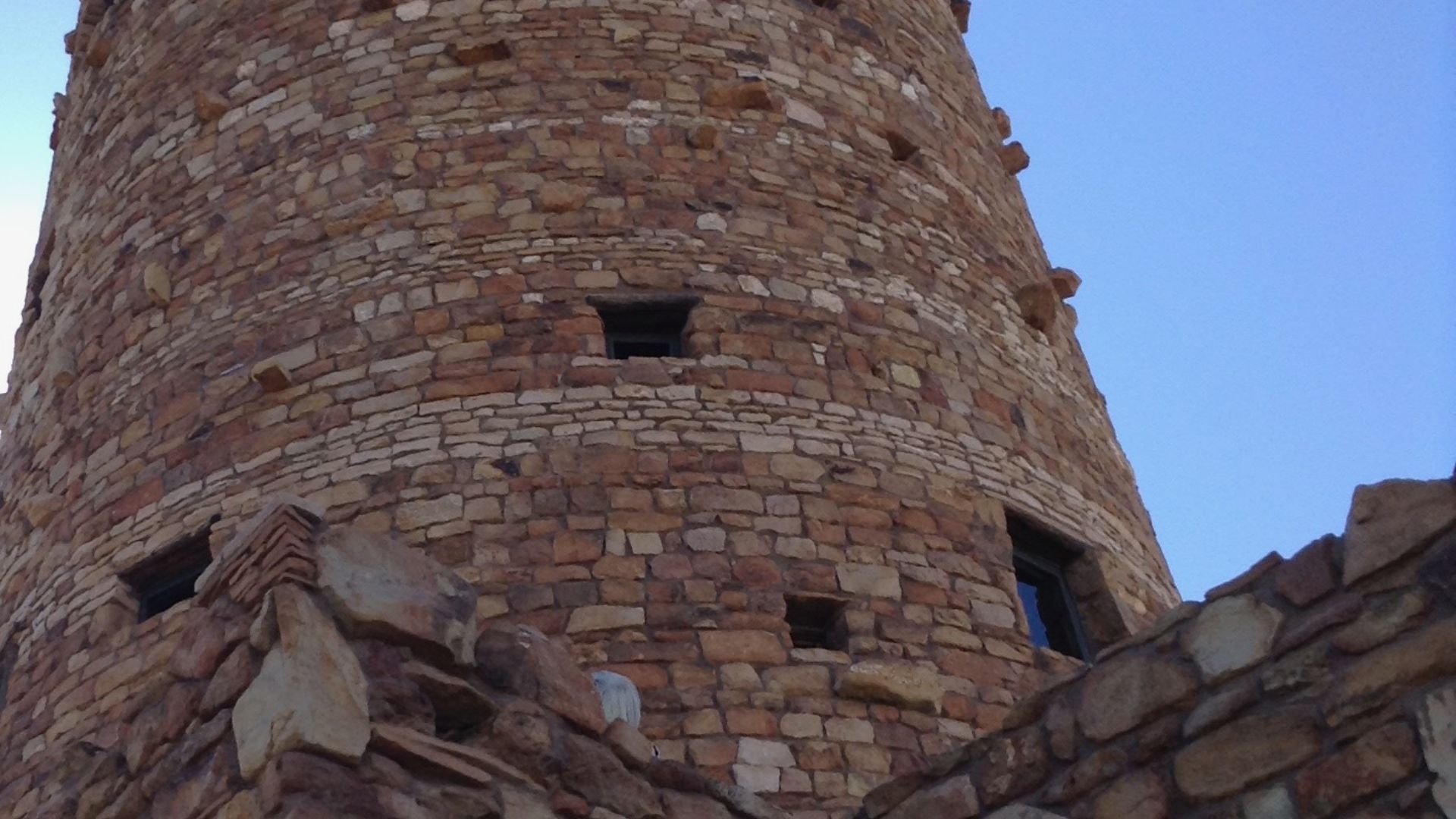Evening falls on the Desert View Watchtower on the Grand Canyon's East Rim 36.0441° N, 111.8262° W. The 70-foot-tall (21 m) rock tower, with a hidden steel structure, was designed by Victorian-era master architect and interior designer Mary Elizabeth Jane