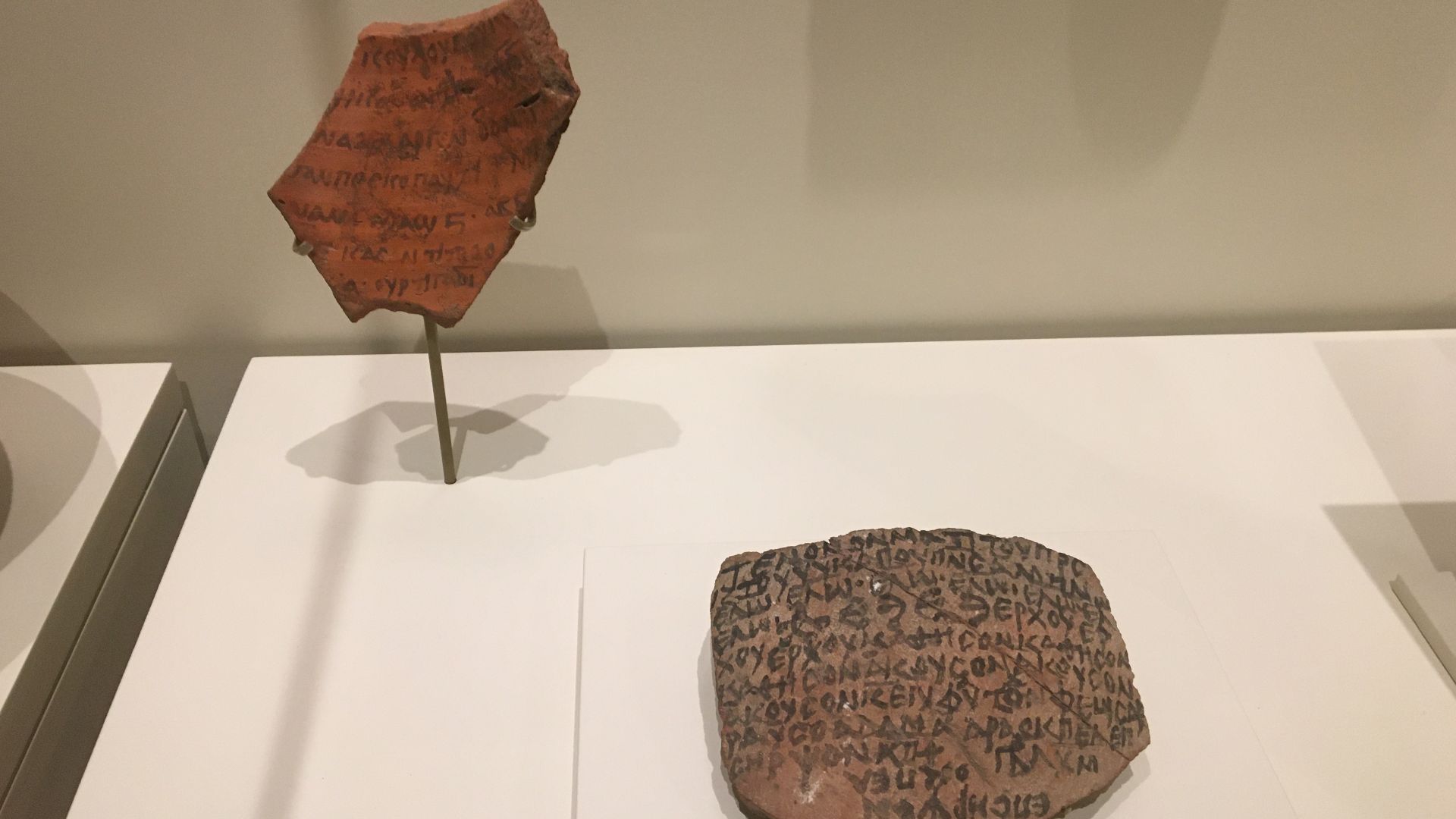 On the left, a pottery fragment with Old Nubian writing. Clay. Gebel Adda, AD 800-1300. And on the right, a fragment with Greek magic text. Clay. Gebel Adda, AD 900-1300.