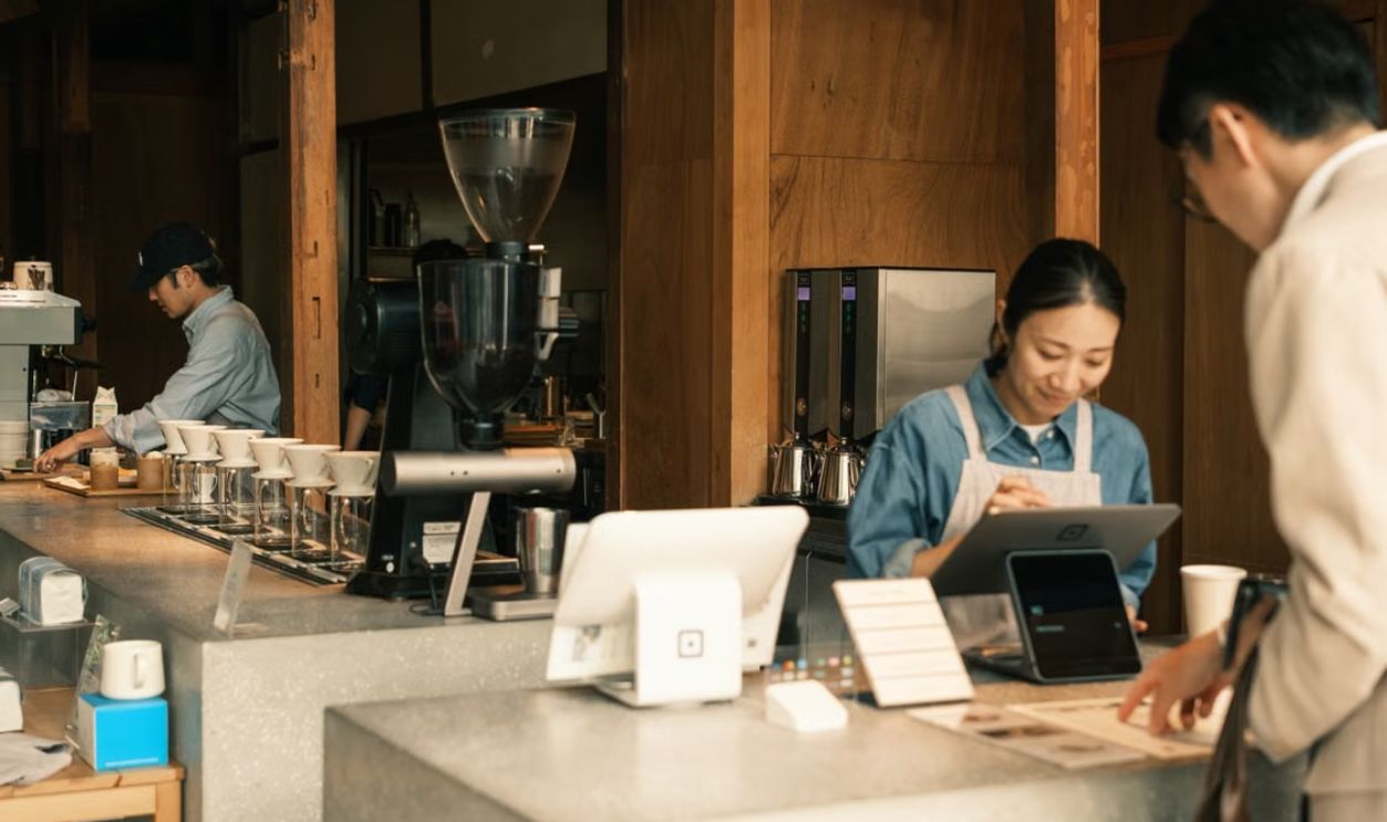 Barista and customers in a cozy Japanese coffee shop, showcasing a modern cafe atmosphere.