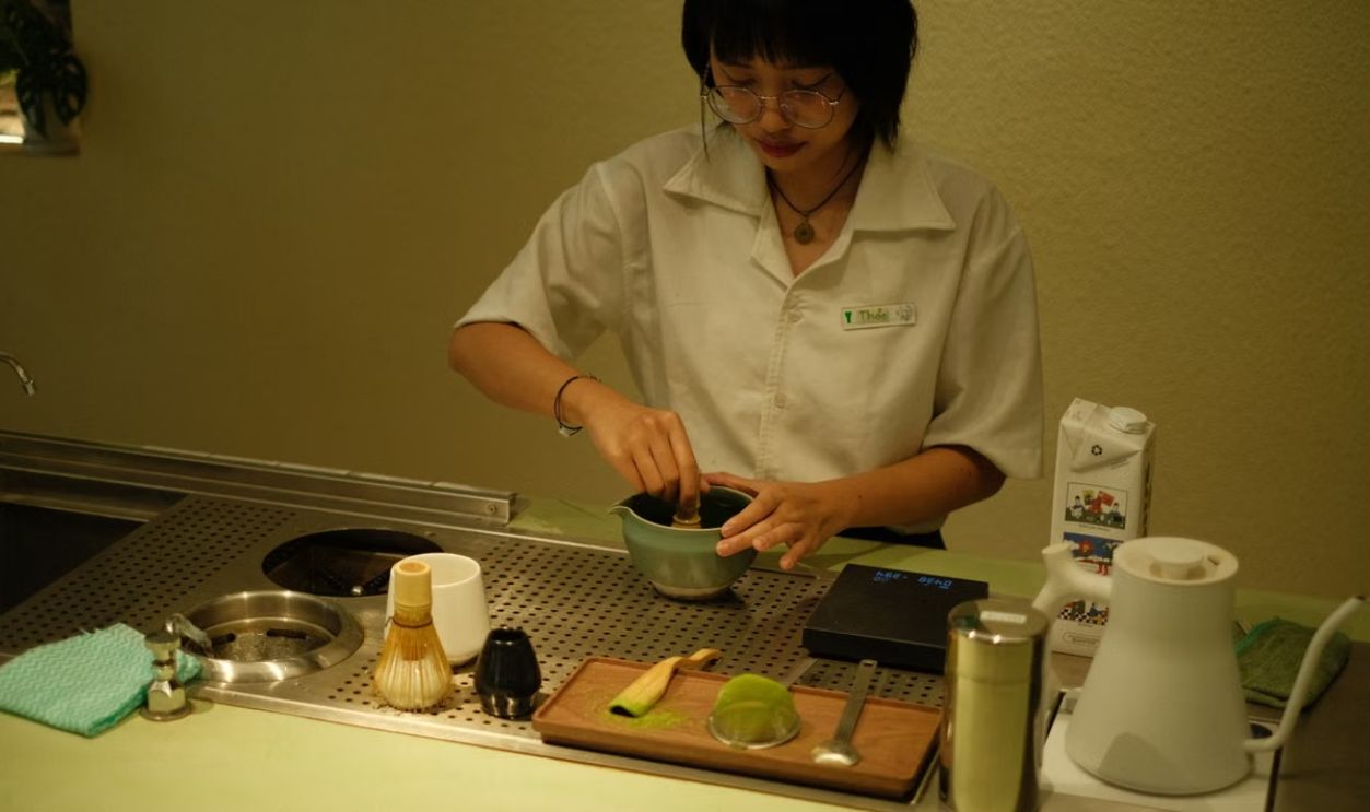 A barista mixing matcha tea in a contemporary tea setting, creating an inviting atmosphere.
