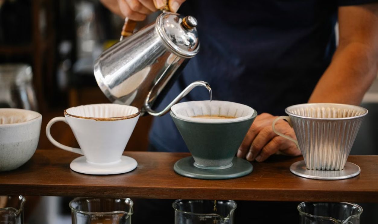 Barista pours water for pour over coffee in a cafe, using a gooseneck kettle.