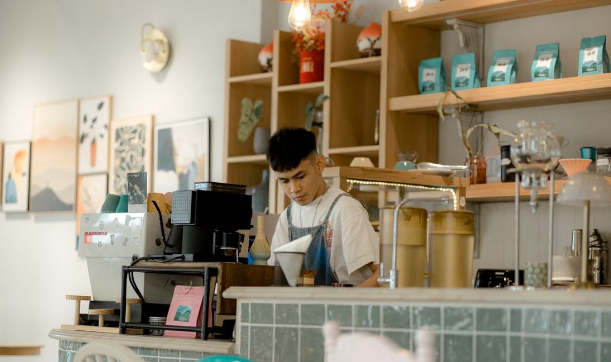 A barista making coffee in a cozy cafe, surrounded by modern interior design and warm ambiance.