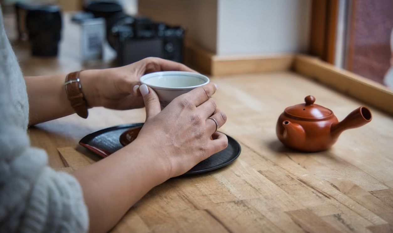 A warm cup of tea in a Berlin cafe, showcasing Japanese teaware on a wooden table.