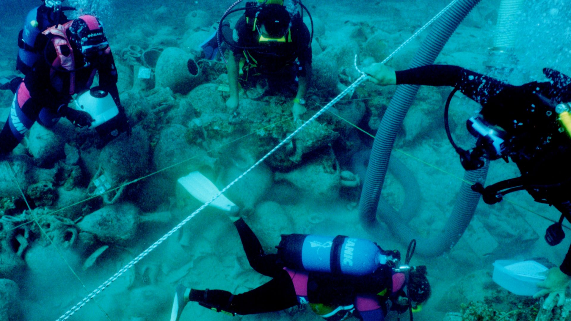 Diving archaeologists excavating the Alonnisos shipwreck in fall 2000, trench Θ3. The 2x2 m rope grid and airlift are visible.