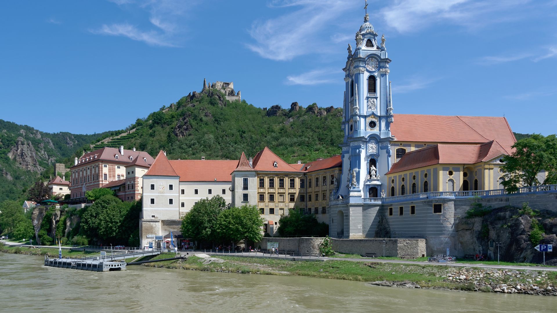 Dürnstein Abbey on the bank of the Danube in Wachau Valley. Ruins of the Dürnstein Castle in the background