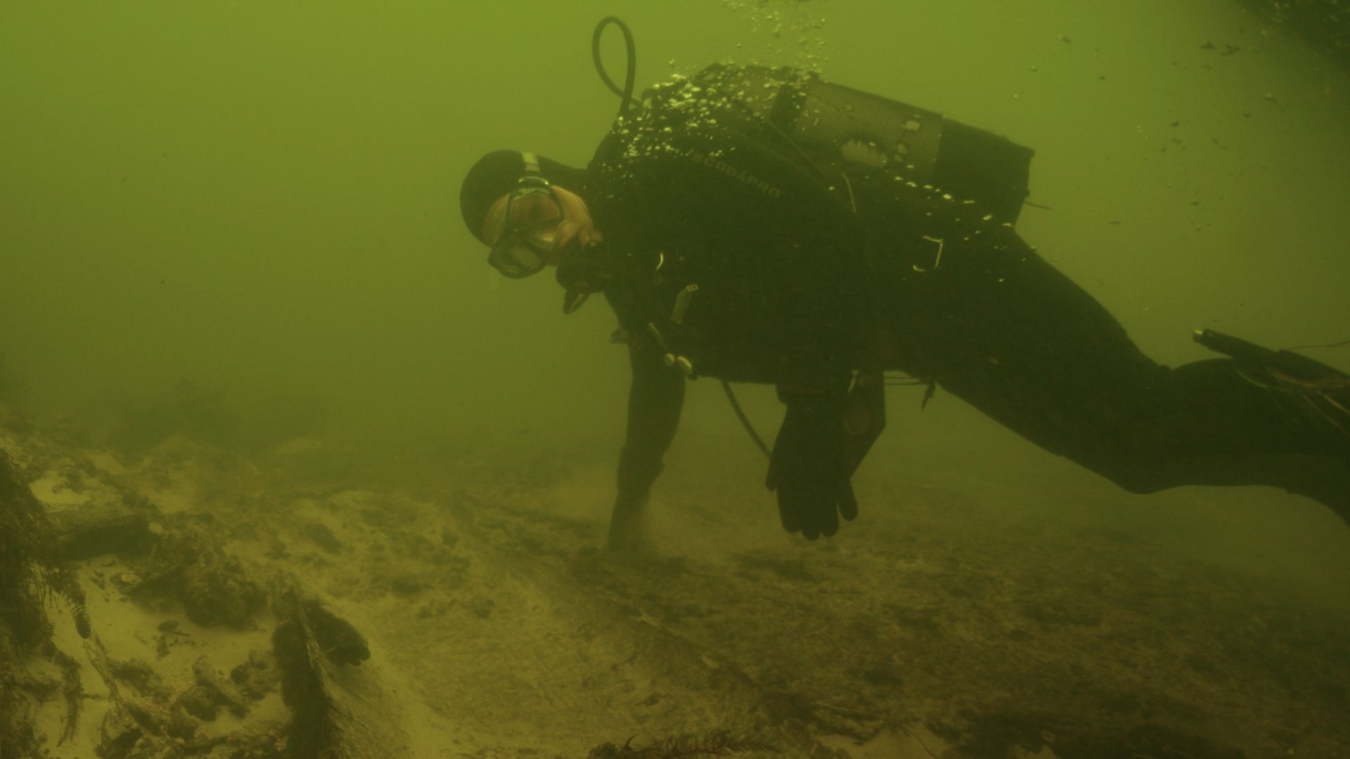 Underwater archaeologist makes a survey of small ancient canoe made from oak tree, Zeimena river, Lithuania