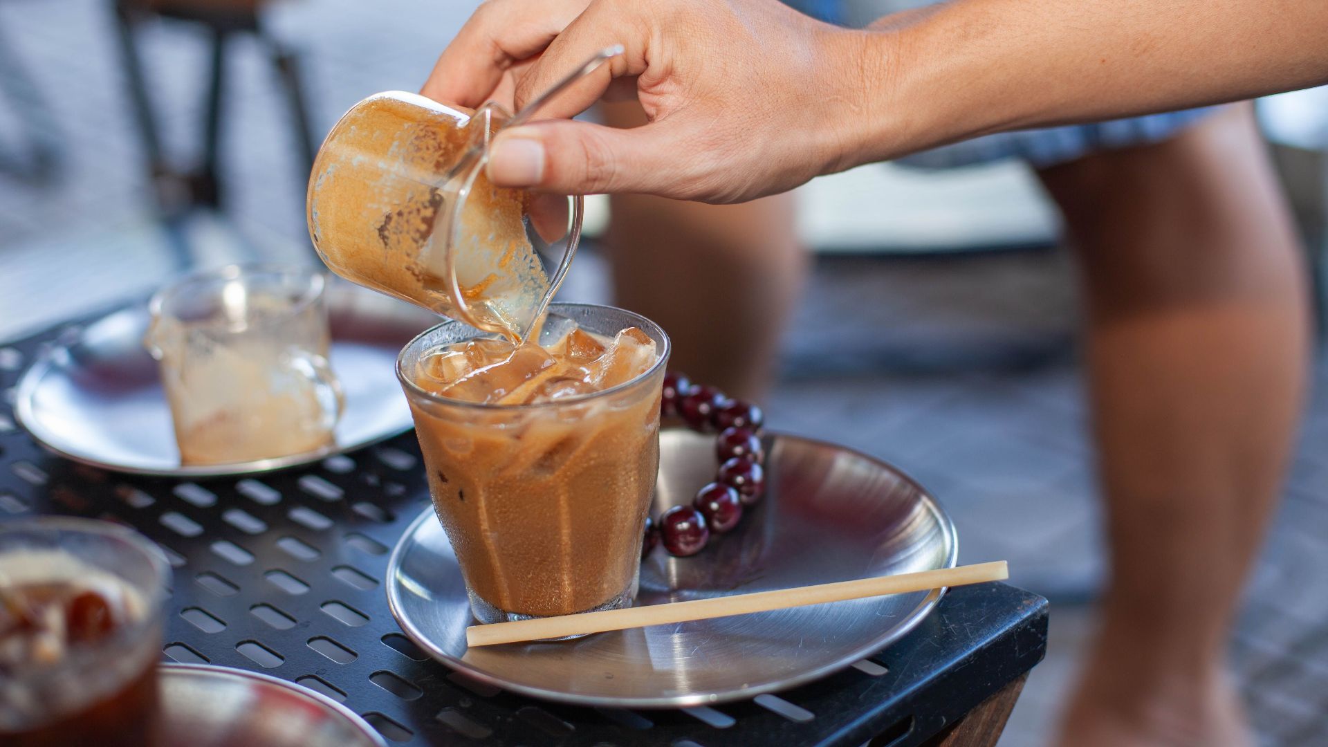 Refreshing iced coffee being prepared outdoors, showcasing coffee culture and summertime vibes.