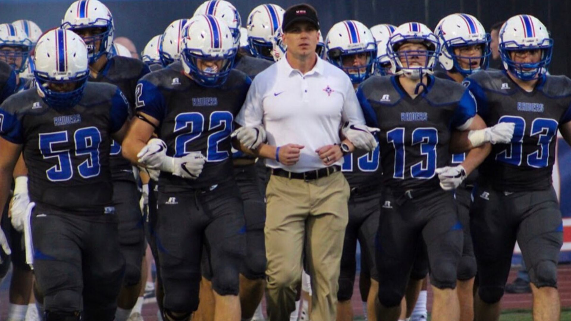 Coach Daniel Brunner leading the Football team out for Friday Night lights.