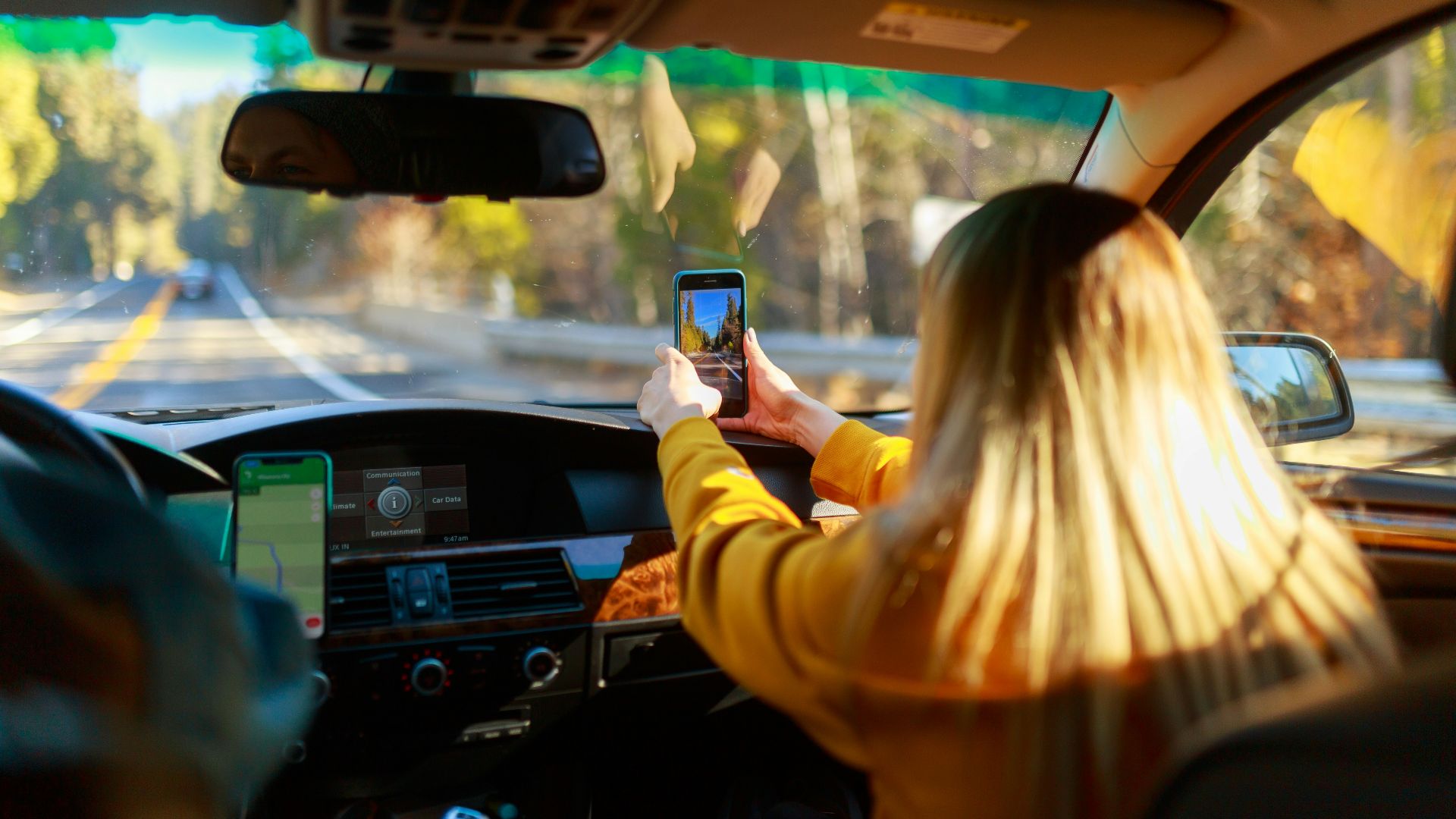 a woman driving a car with a cell phone in her hand