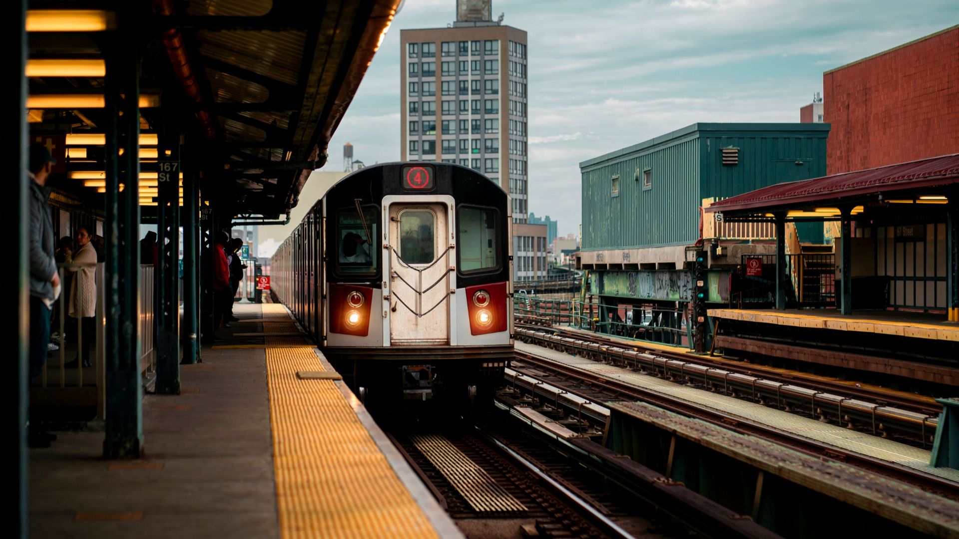 A subway train arriving at a Bronx station in New York City during the day.