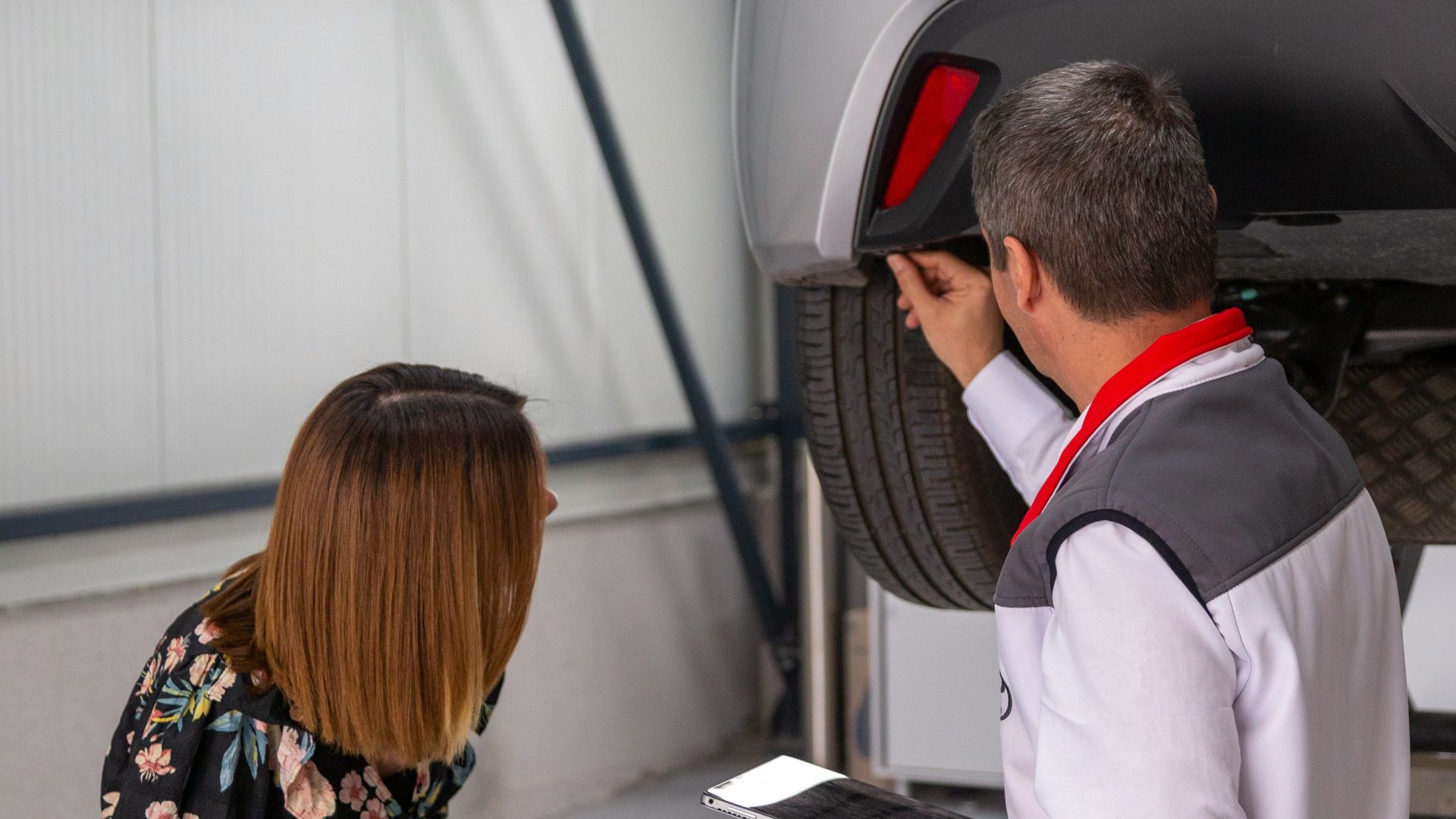 A man and a woman looking under a car