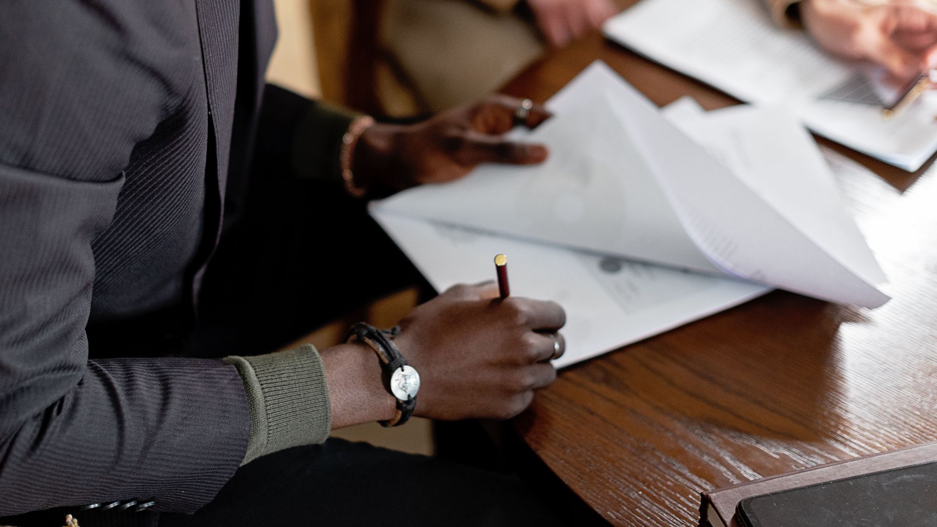 African American man focused on signing important business documents at a desk.