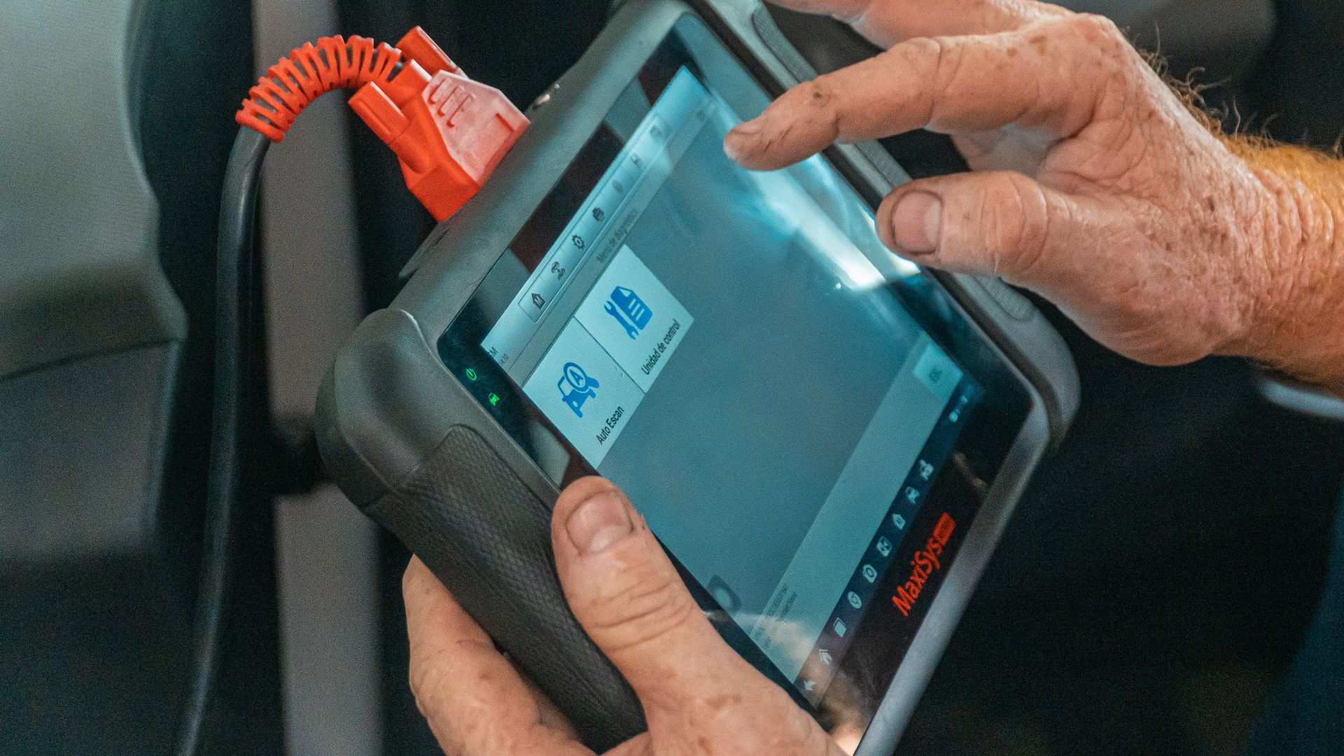 Mechanic using a diagnostic tool inside a car to check for engine issues and ensure proper maintenance.